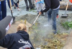 Fish cooking underground is uncovered June 21 by the Jordan River during the Pacheedaht First Nation’s celebration of its acquisition of their ancestral land.  