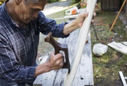 Joe Martin carves the bone of a grey whale outside his workshop.