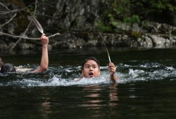 Ethan Joseph starts his way back across a river holding a feather, after swimming through the frigid water to receive it from Andrew Clappis Jr. (Eric Plummer photo)