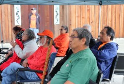 Survivors gathered under shelters in front of the Indian residential school memorial sculpture.