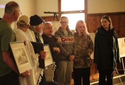 Margaretta James speaks while others stand to recognize the late historian Robin Inglis.