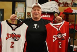 Mike Roberts holds up brand new ADSS junior team Storm basketball jerseys.