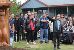 Artist Joe Martin explains the figures on a new totem pole to a crowd at Tin Wis.