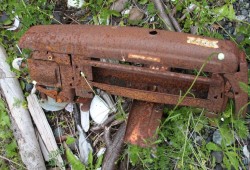 A rusted clothing press is found in the grass at Nuchatlitz.