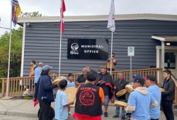Tla-o-qui-aht First Nation and the District of Tofino raise three flags – Tla-oqui-aht, Canada and B.C. – outside the municipal office on Aug. 4.