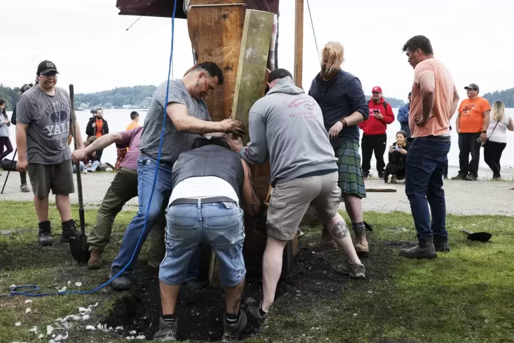 Gordon Dick (second left) helps to pack the soil down around the totem pole after itÕs raised, in Opitsaht, on Meares Island, on July 1, 2022.