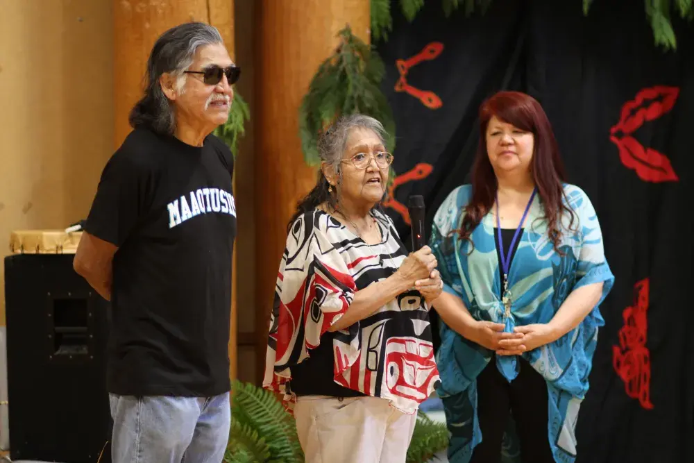 Ahousaht elder Ciisma speaks to the crowd at the Port Alberni Friendship Center, alongside Executive Director Cyndi Stevens and fellow Ahousaht elder Wally Samuel. (Eric Plummer photo)