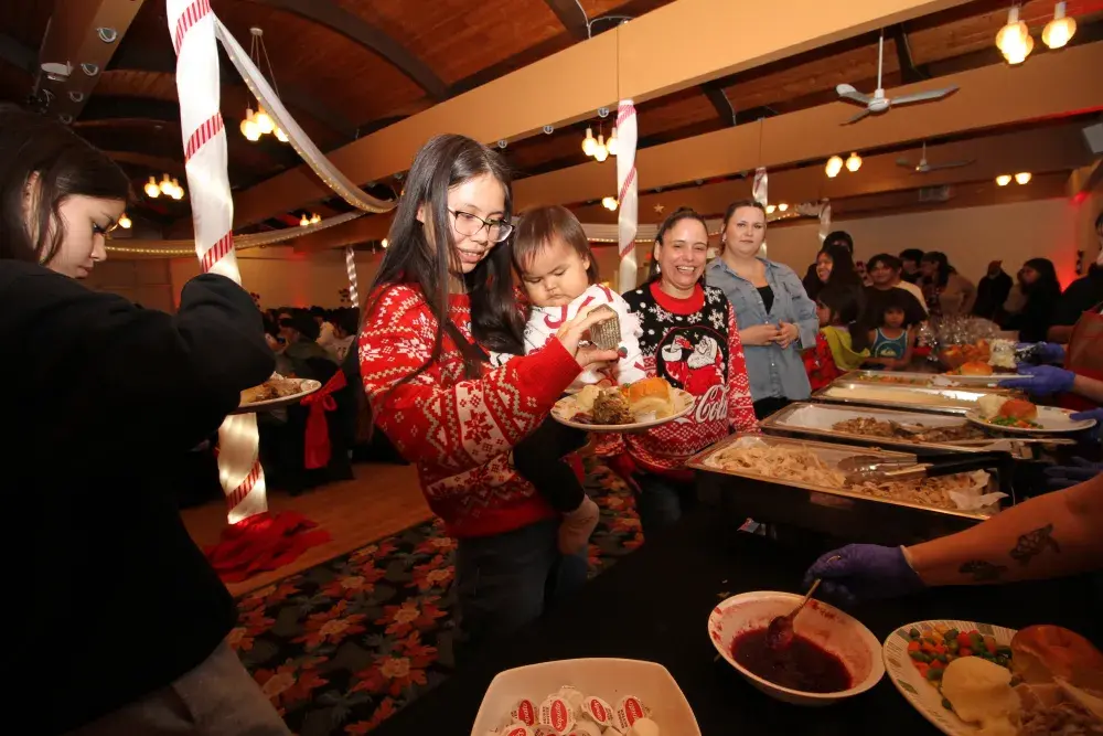 Ciara Joseph holds Savannah Joseph-Frank, gathering a plate of food with Jolen Joe and Saphiah Lauder at Port Alberni's Italian Hall on Dec. 10.