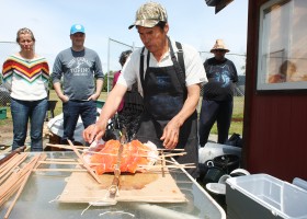 Weaving some outside cedar strips to secure the cross sticks that keep the splayed salmon from dropping in the fire